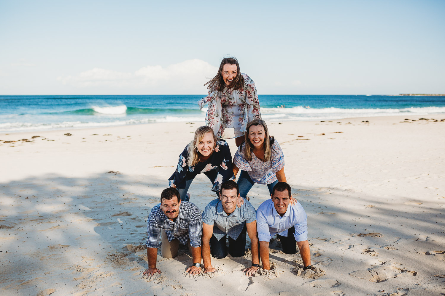Adults in family smiling while forming human pyramid