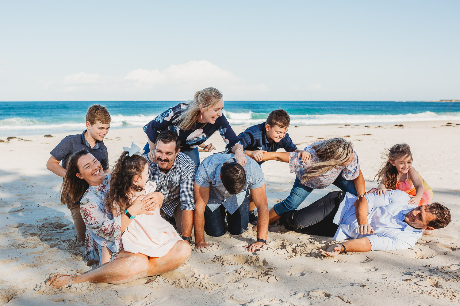 Family laughing and smiling while attempting human pyramid and falling