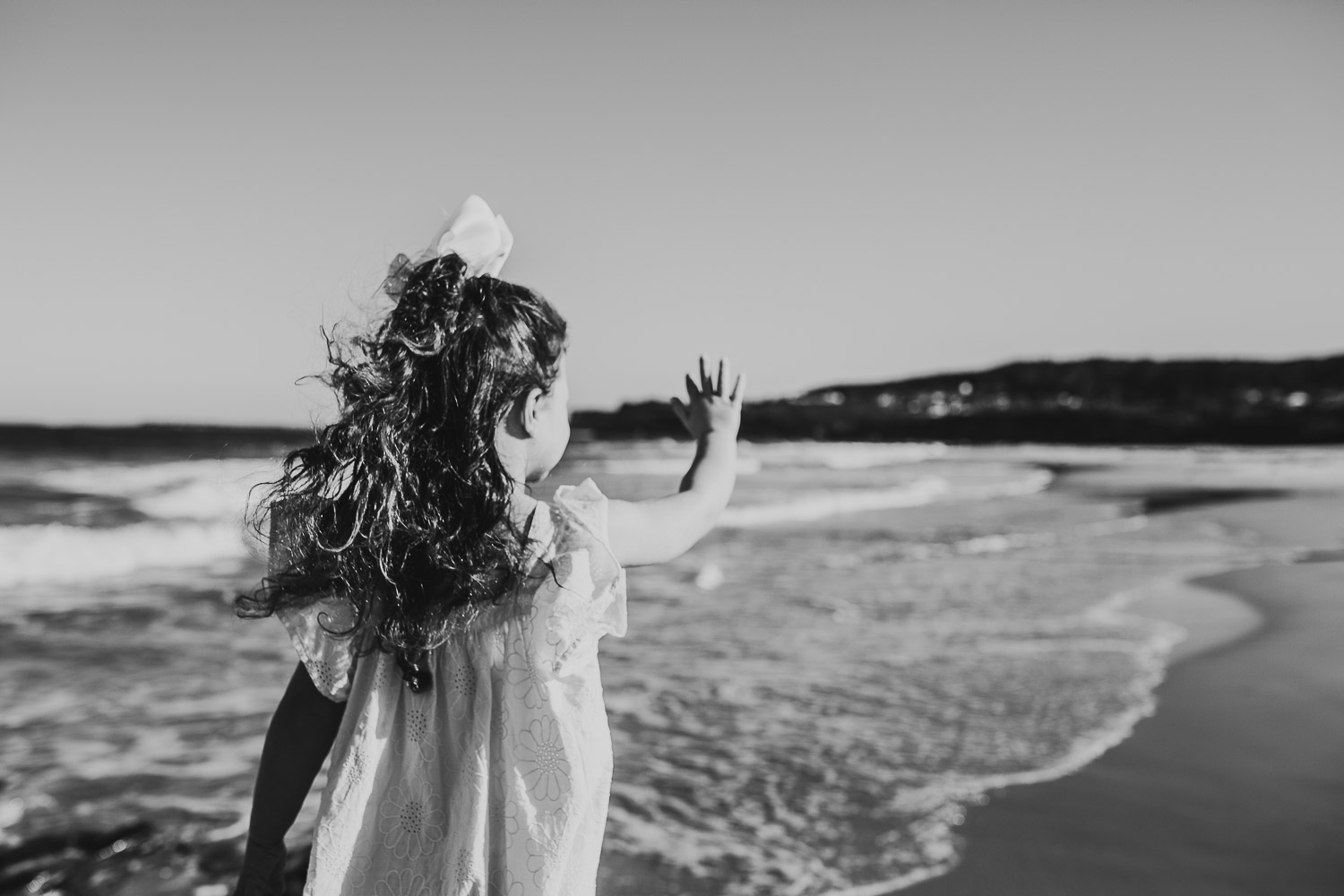 Black and white image of young girl facing away at the beach
