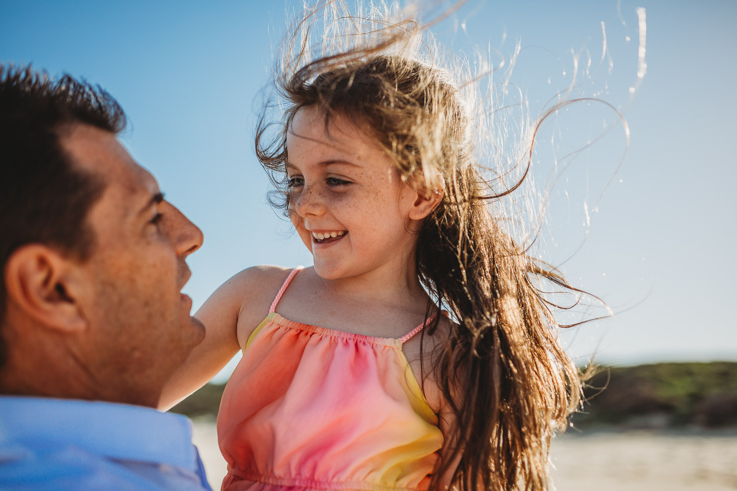 Young girl with windswept hair smiling at her father