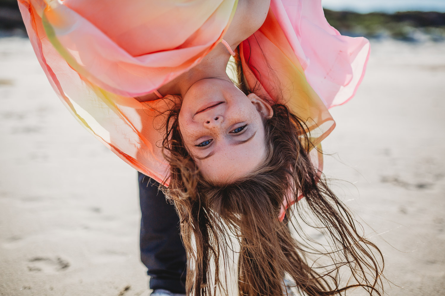 Young girl hanging upside down smiling