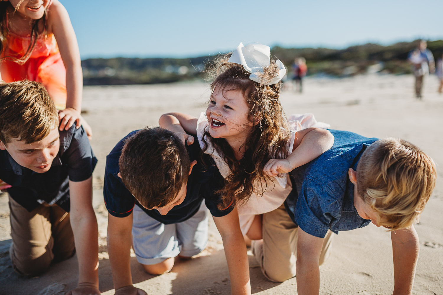 Girl falls laughing while forming human pyramid with cousins
