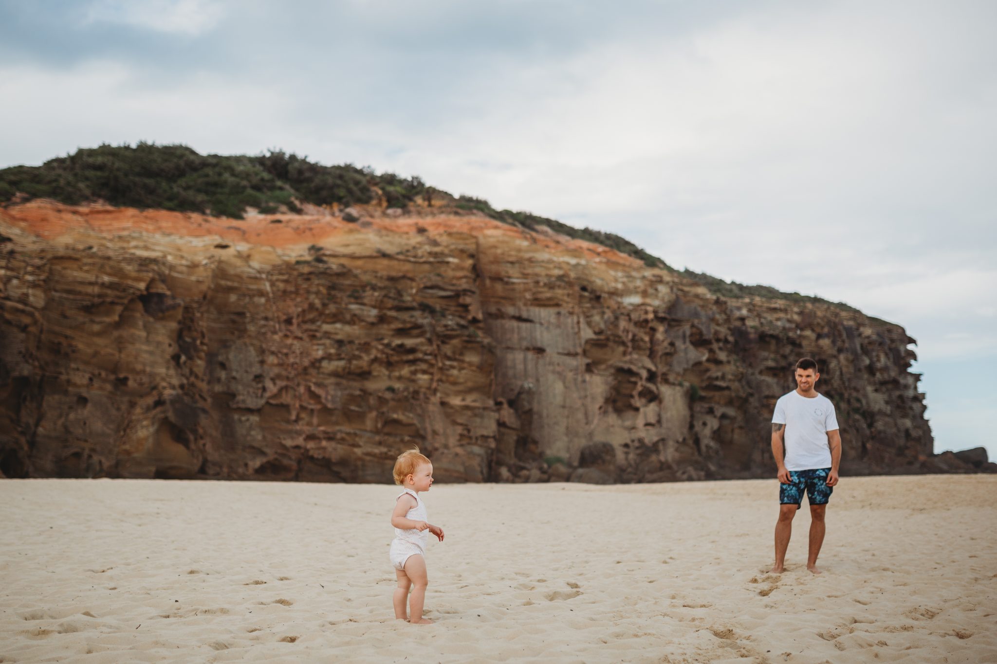 Father and toddler daughter standing on the beach