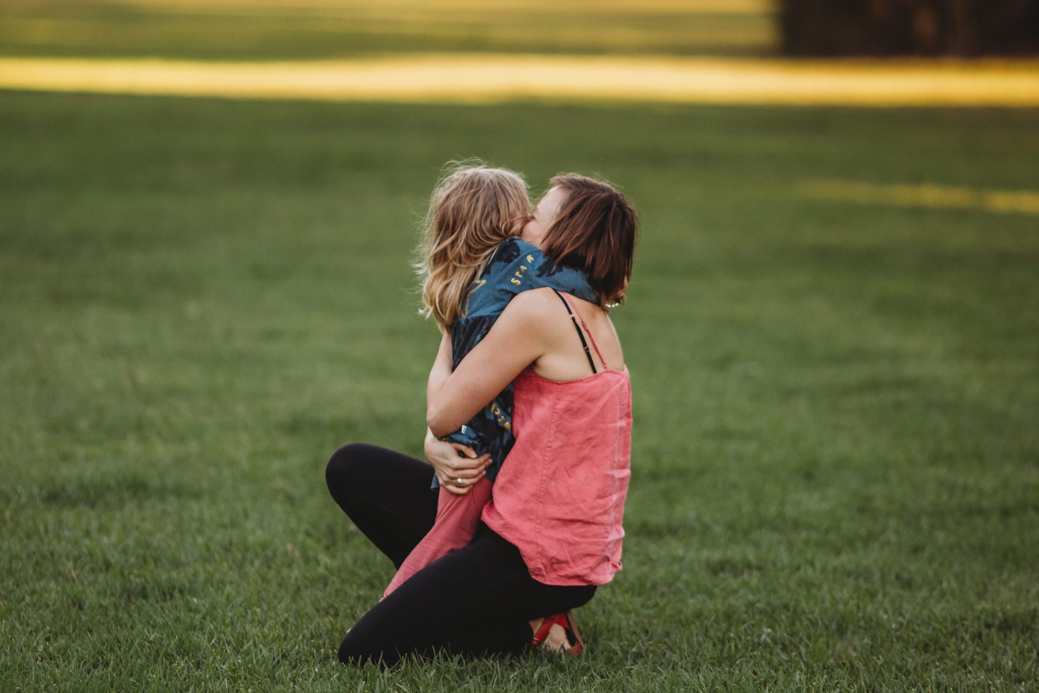 Woman kneeling to hug her young daughter
