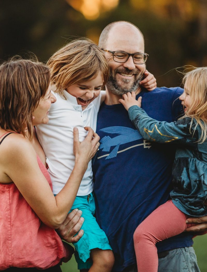 Young parents holding their son and daughter as they all tickle each other