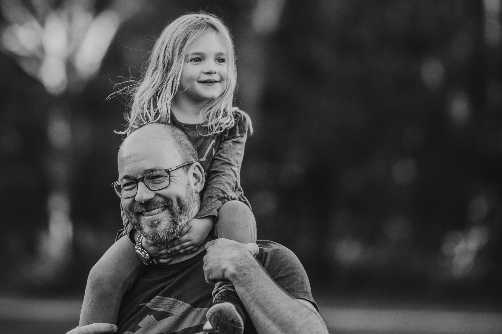 Black and white image of girl on her dad's shoulders
