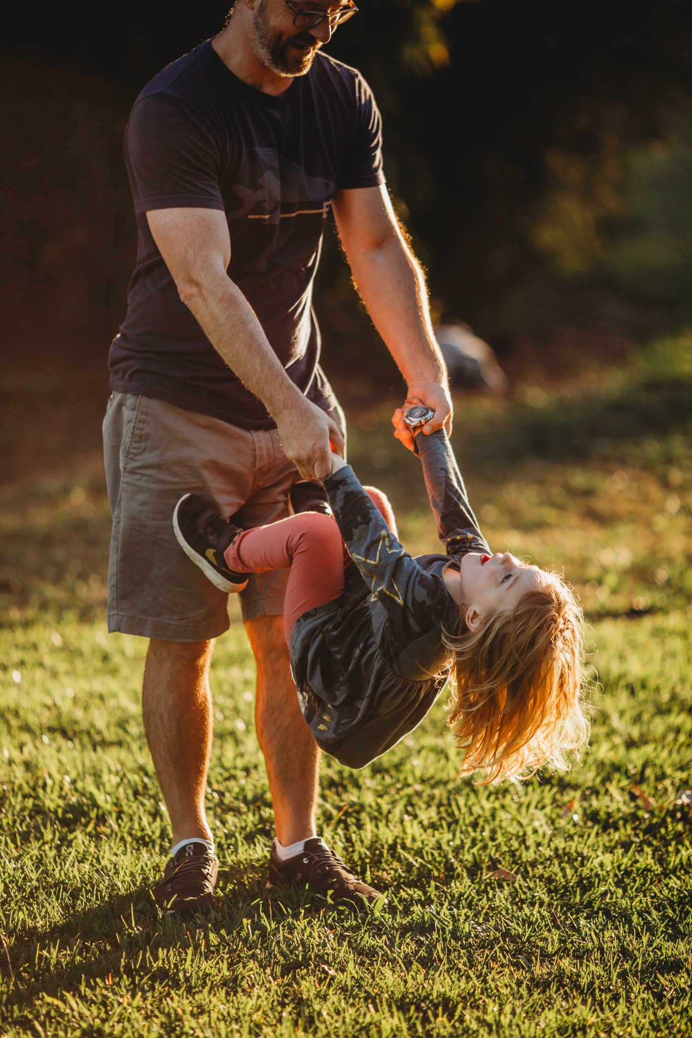 Man flipping his daughter upside down while holding her hands