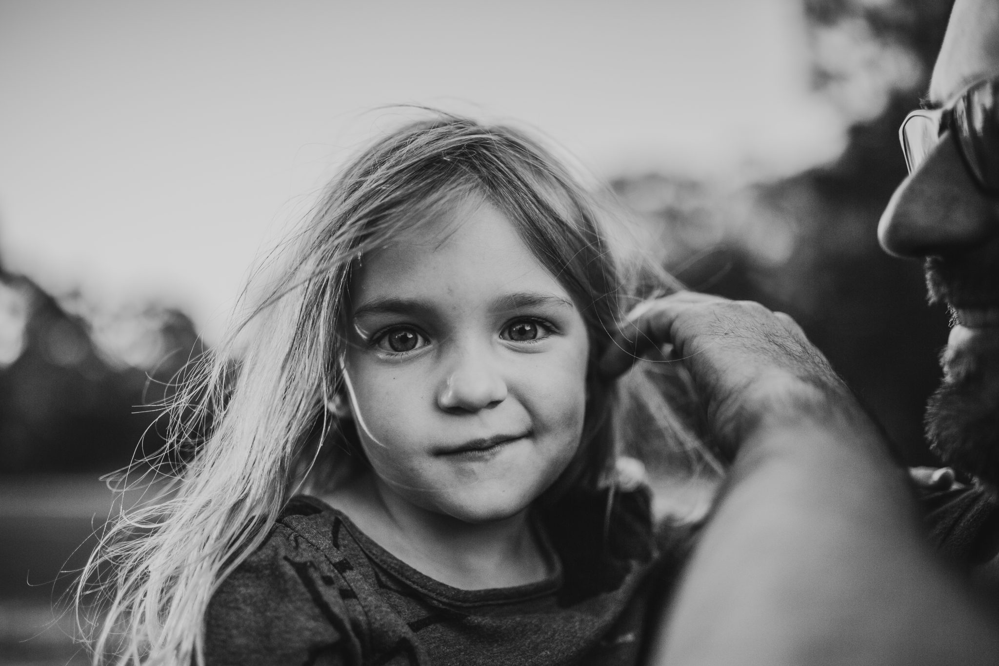 Black and white portrait of father brushing hair away from daughter's face
