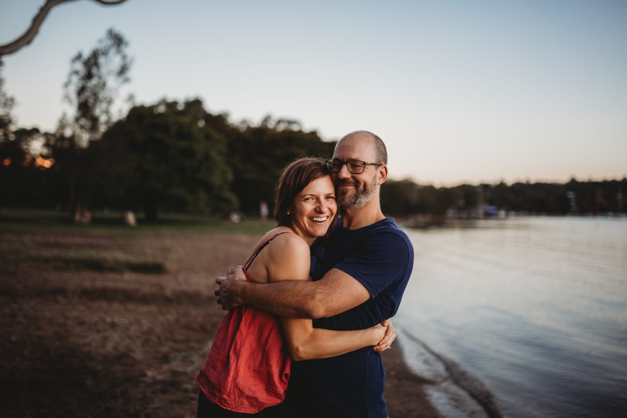 Woman and man hugging and smiling by Lake Macquarie