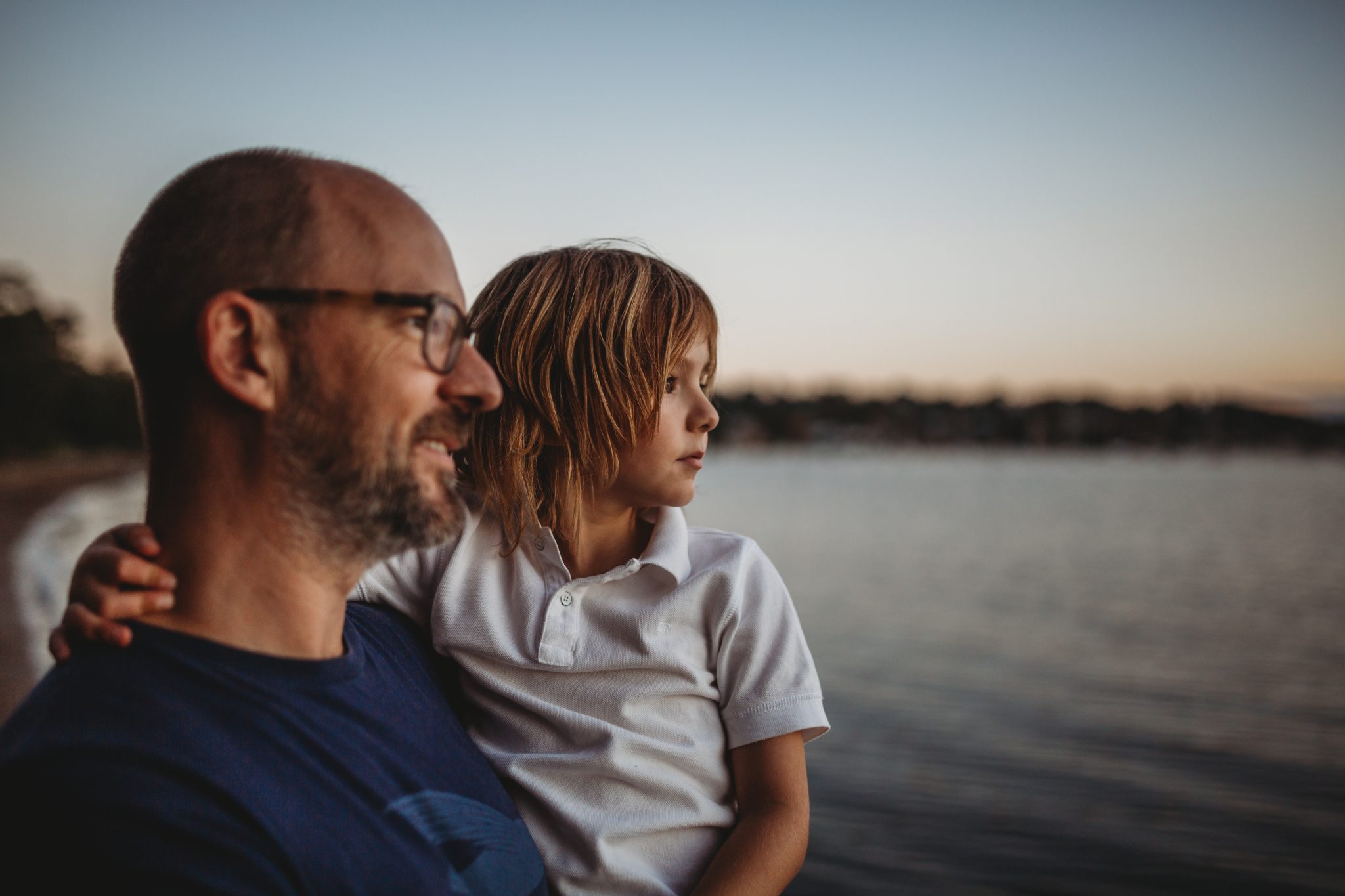 Young boy and father looking out to Lake Macquarie at sunset
