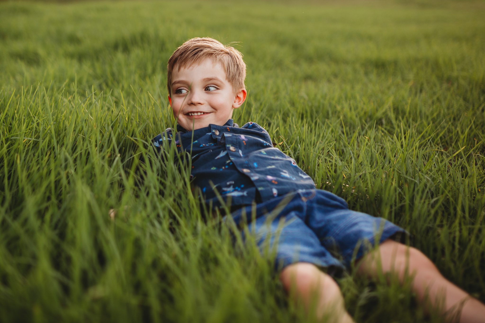 Boy smiling, laying in long grass