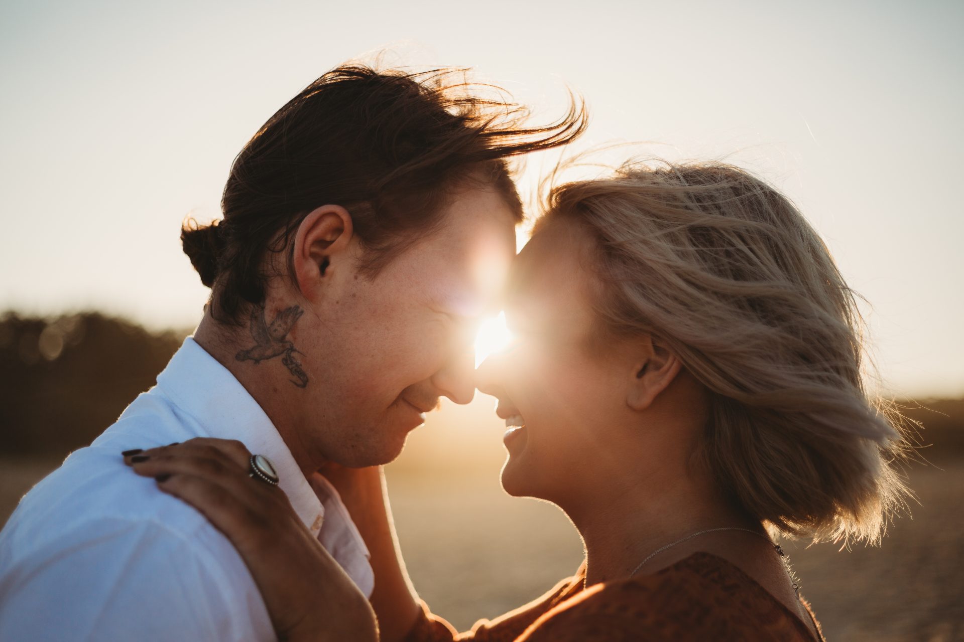 Sun flare between the faces of young couple touching faces together