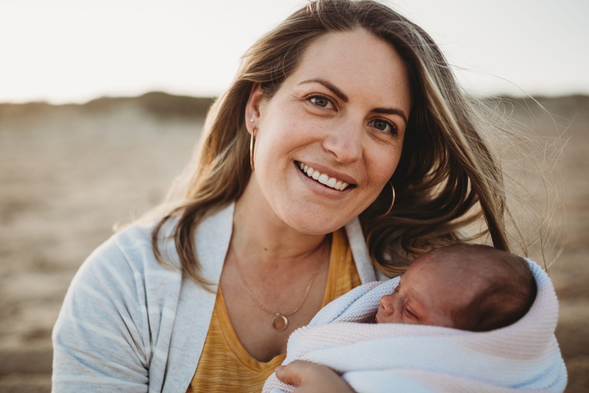 Woman smiles at camera while holding her baby daughter