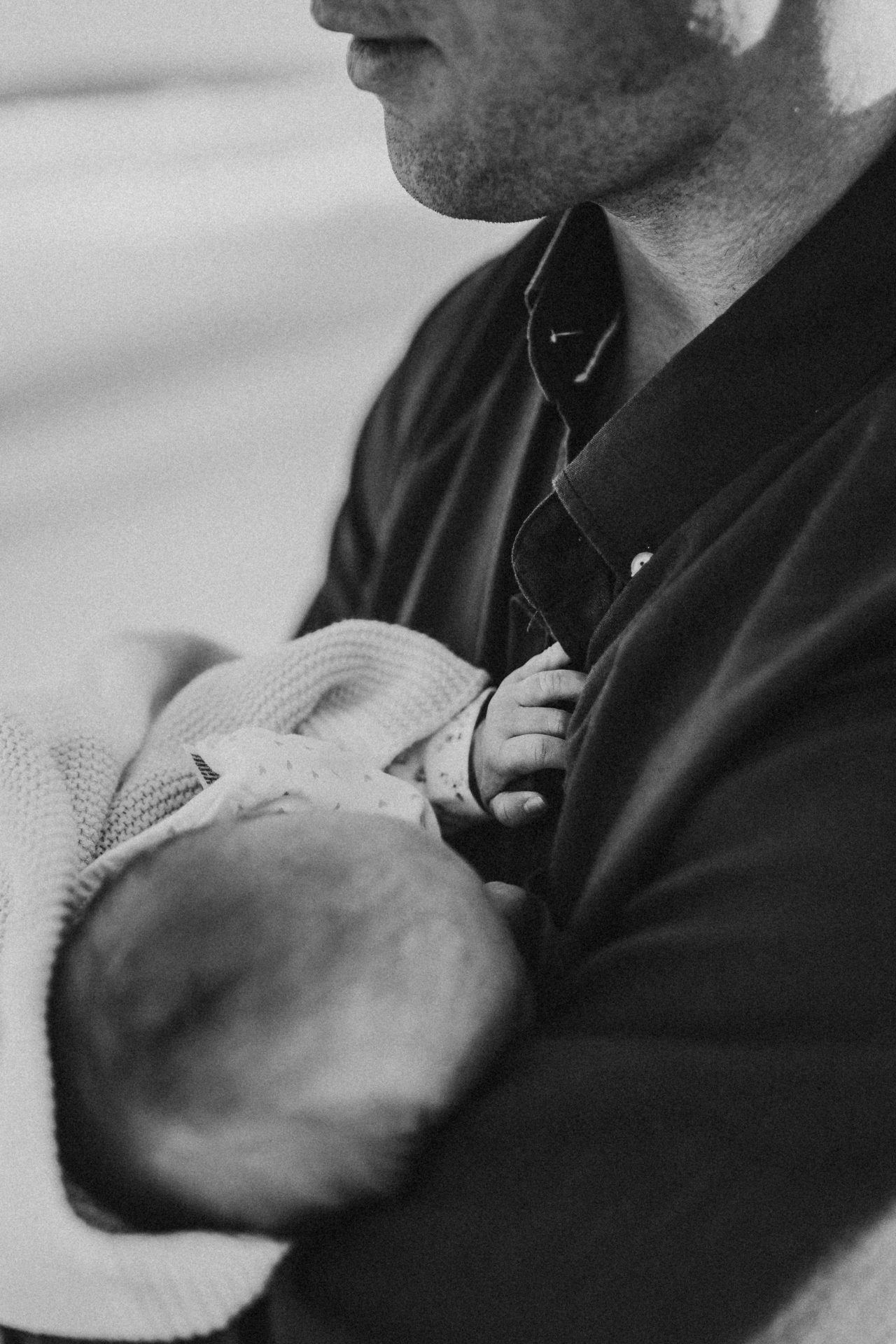 Black and white close up of baby's hand resting on her father's chest