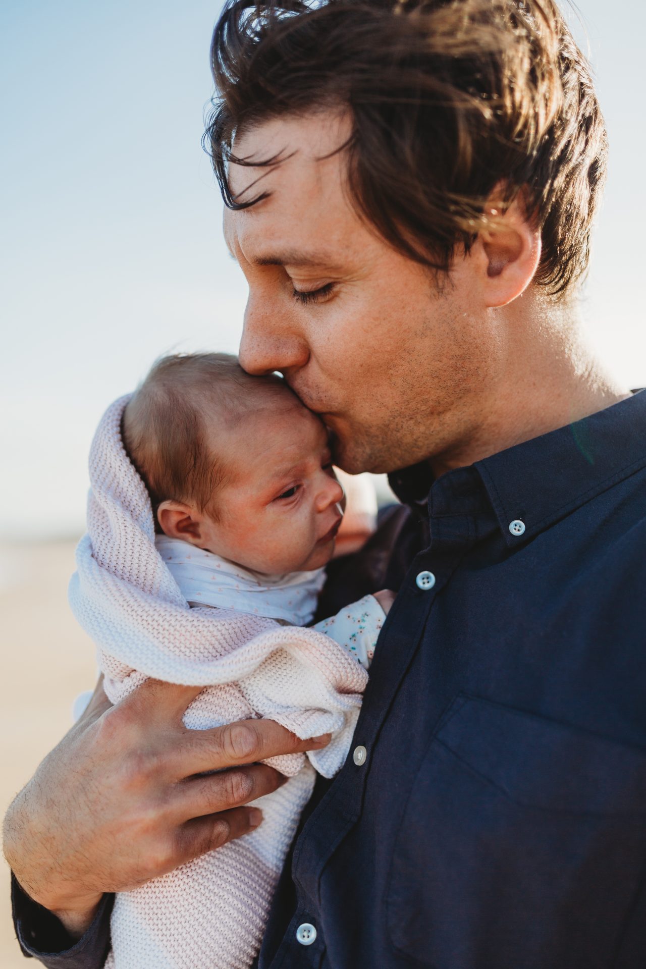 Man holding baby daughter close and kissing her head